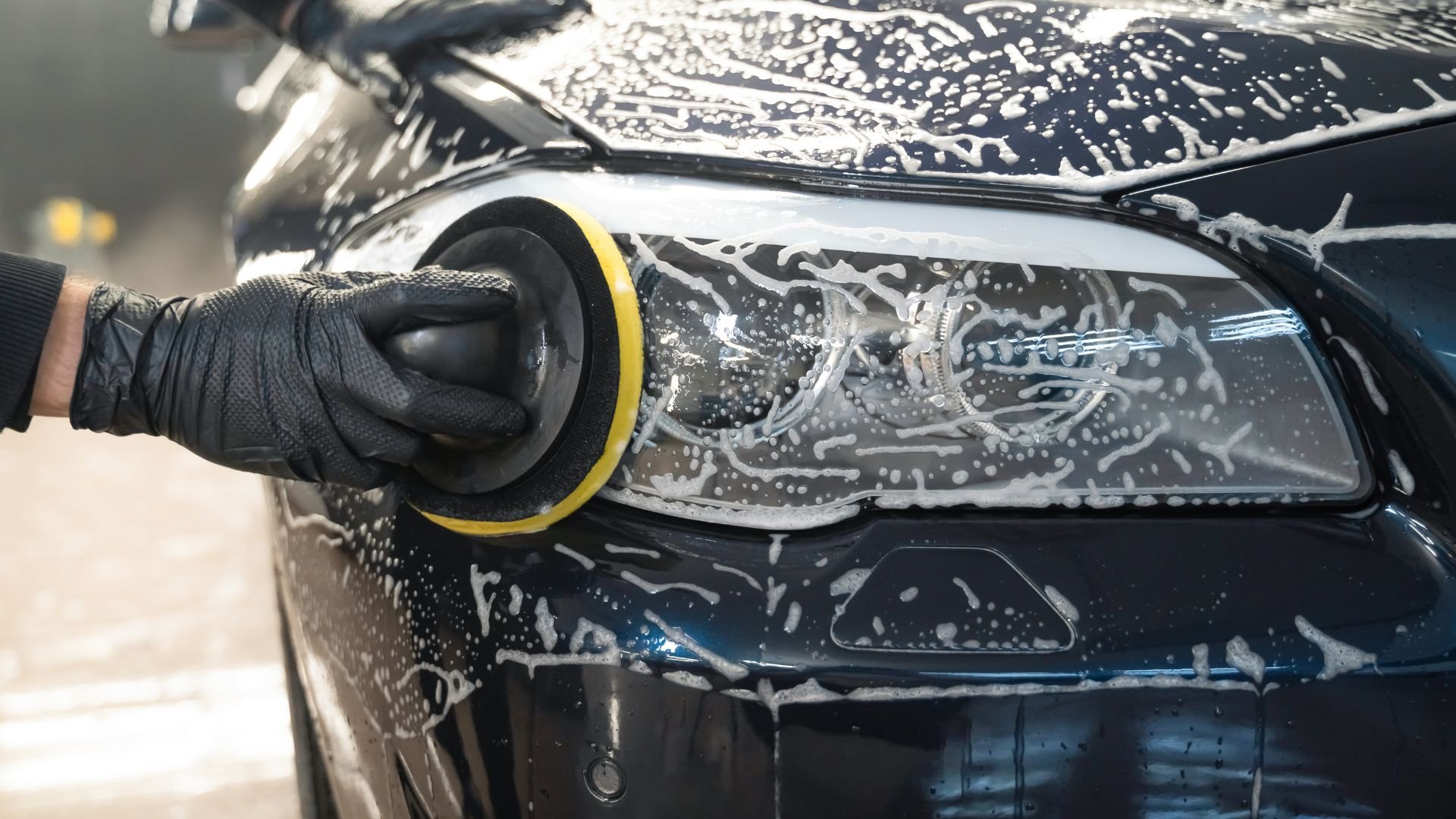 Polishing car headlight with buffer pad during detailing process