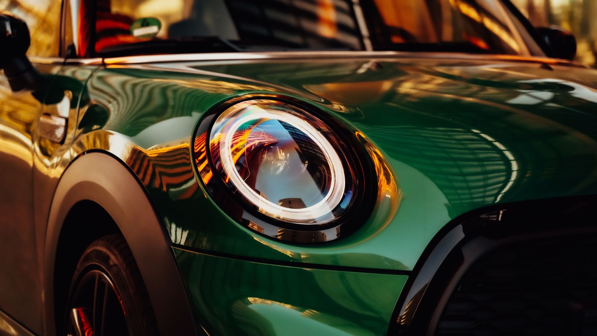 Close-up of a green classic car headlight with reflective golden highlights