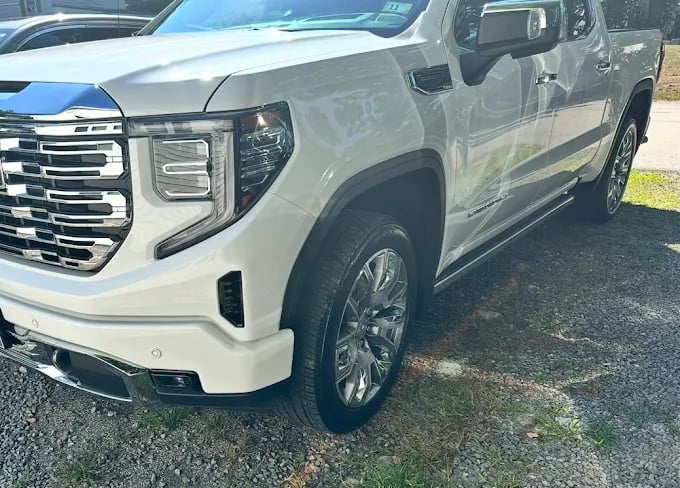 White GMC Sierra pickup truck parked on gravel with shiny chrome details