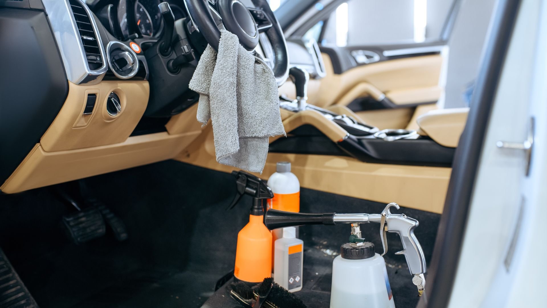 Car interior with cleaning supplies, spray bottles, and microfiber towel