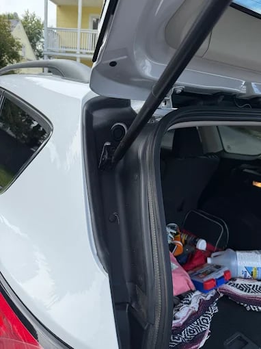 White car with open door revealing colorful items inside trunk