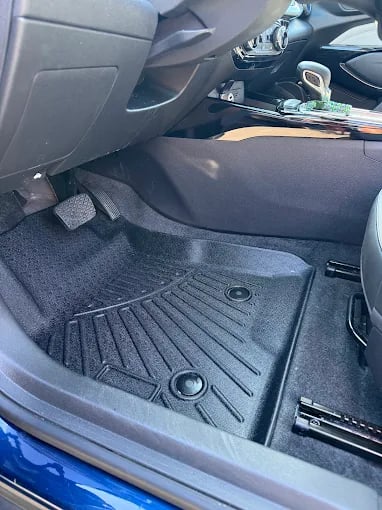 Black car interior floor mat with textured surface and mounting points